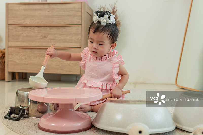 可爱的亚洲小女孩在家玩着粉色厨房玩具图片素材