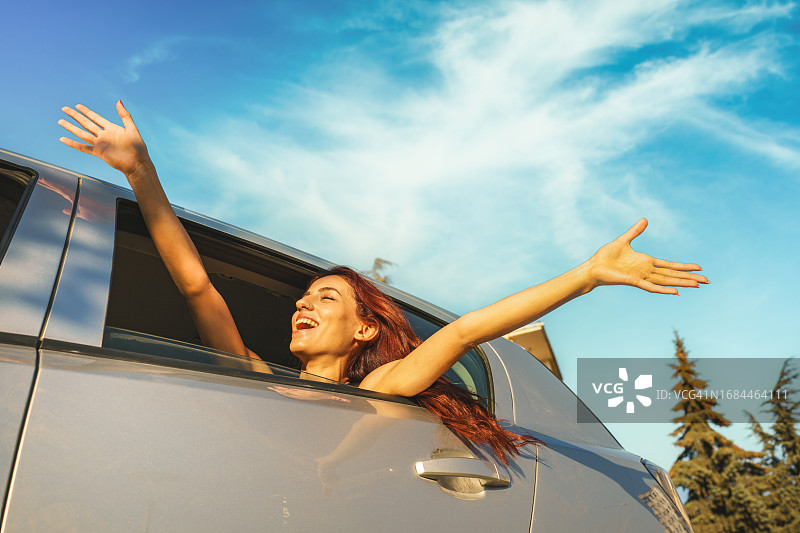 年轻女子喜悦地看着车后窗外图片素材