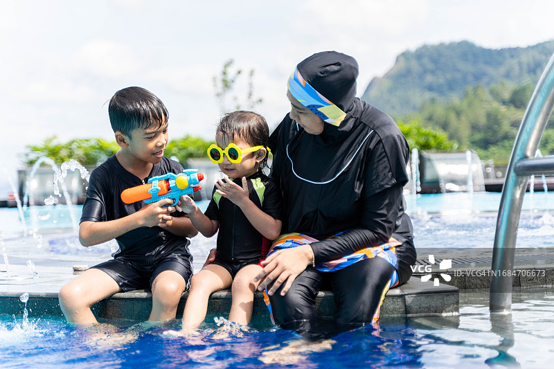 母亲高兴地和孩子们一起玩水枪图片素材