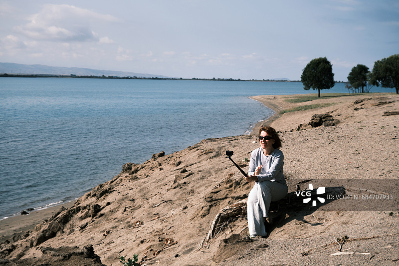 46岁的妇女在湖岸边录制自己的视频图片素材