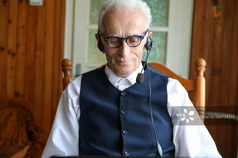 快乐的中年男人在家通过电脑在电话会议中向某人问好图片素材