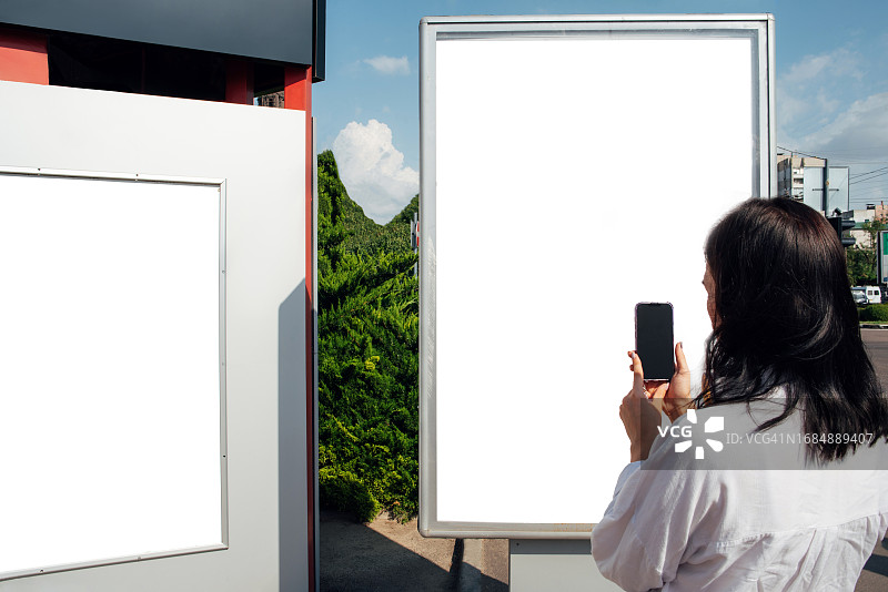 一位女士站在户外的广告banner旁。户外广告。城市。生活方式。文字和任何设计背景图片素材
