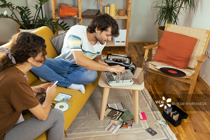 年轻男人和他的女朋友寻找旧音乐CD并享受复古音乐图片素材