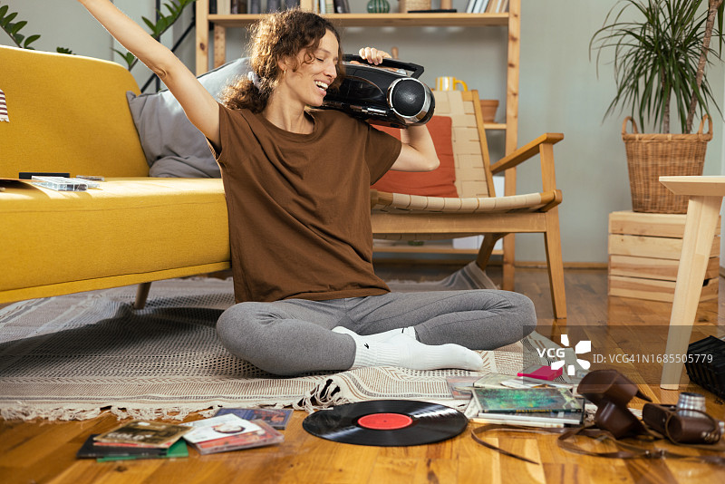 快乐的年轻女人用老式便携式立体声音响欣赏音乐图片素材