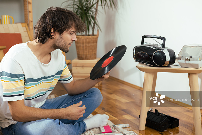 年轻男人在家欣赏旧音乐唱片和磁带的肖像图片素材