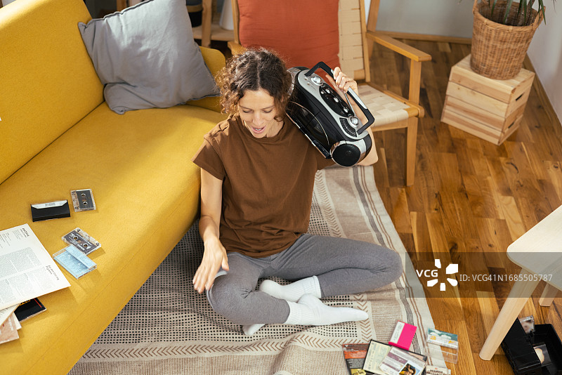 快乐的年轻女人用老式便携式立体声音响欣赏音乐图片素材