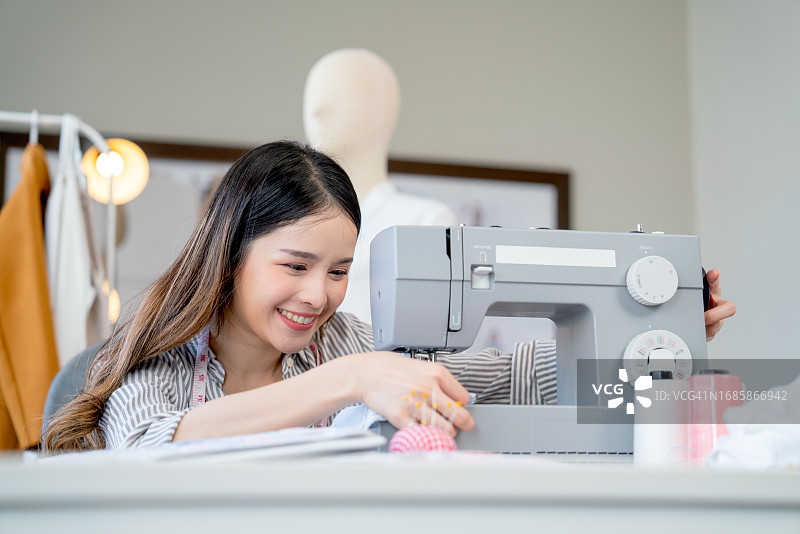 亚洲年轻设计师在办公室使用缝纫机工作特写图片素材