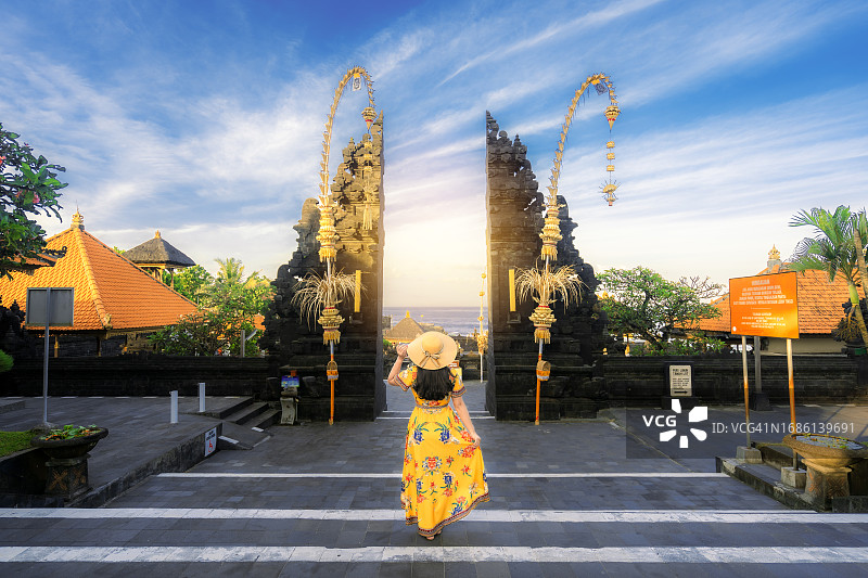 年轻女子身穿黄色连衣裙，在印度尼西亚巴厘岛的塔拿律寺庙前图片素材