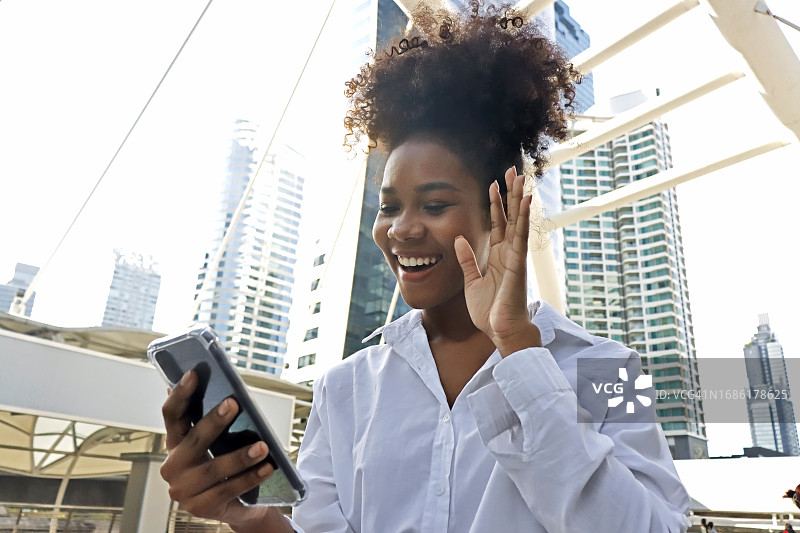 生活与科技：年轻女商人在城市中使用智能手机进行视频聊天，快乐的商业女性享受户外阳光图片素材