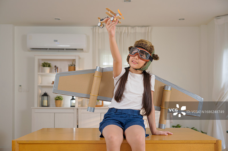 带着火箭翅膀，假装在天空中飞翔的可爱女孩图片素材