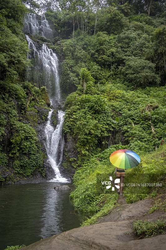 女人在印度尼西亚巴厘岛Banyumala双瀑布附近撑伞图片素材