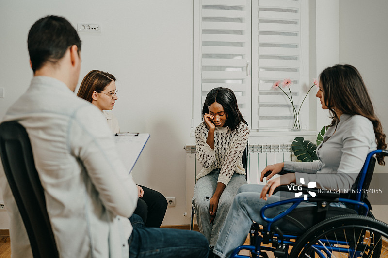 不同种族的年轻女人与男精神科医生进行咨询，包括坐在轮椅上的女人图片素材