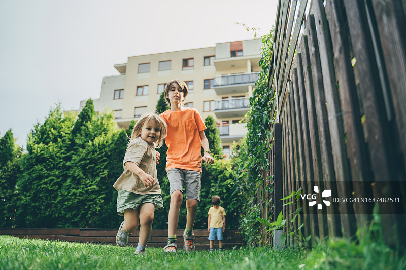 孩子们在草坪上奔跑，一个小男孩站在他们身后，有些悲伤图片素材