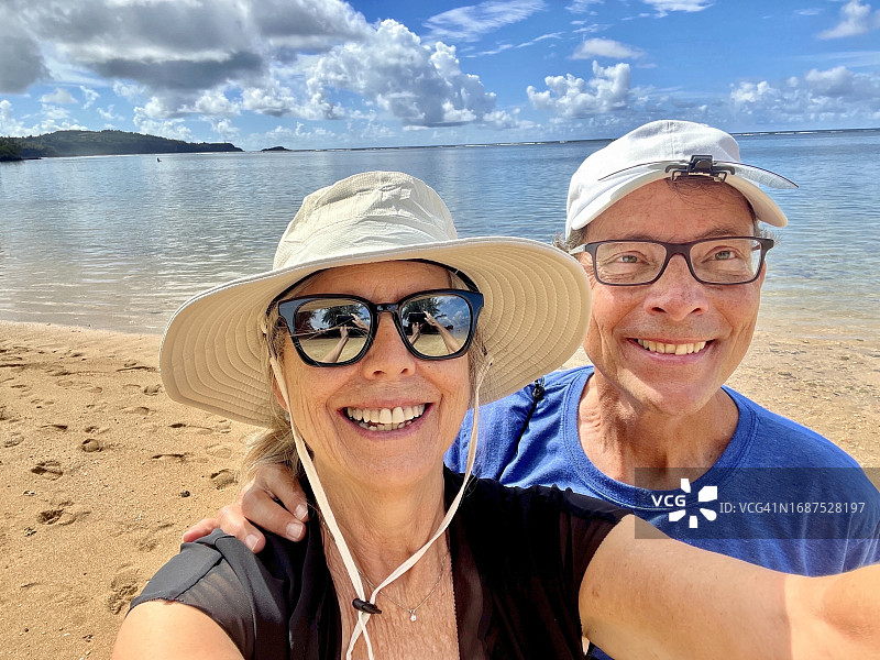活跃的老年夫妇在考艾岛海滩上自拍，背景是海水和天空图片素材