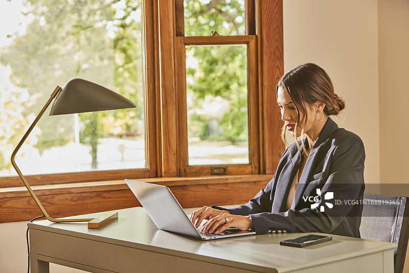 女人在家里的桌子旁使用笔记本电脑图片素材
