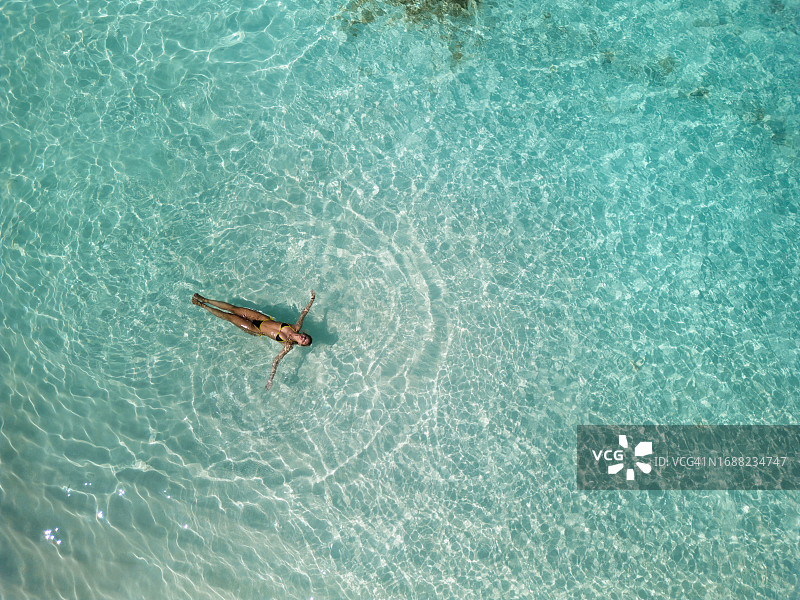 无忧无虑的女人漂浮在海中的俯视图图片素材