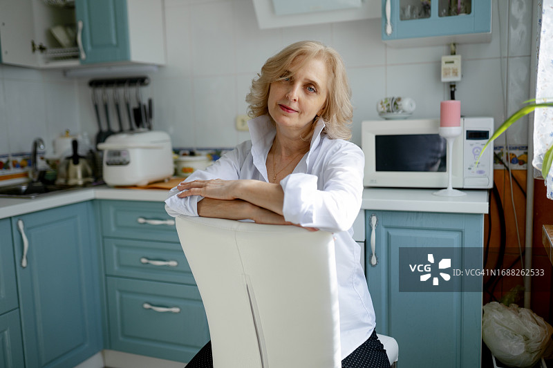 坐在厨房椅子上看着镜头的女人图片素材