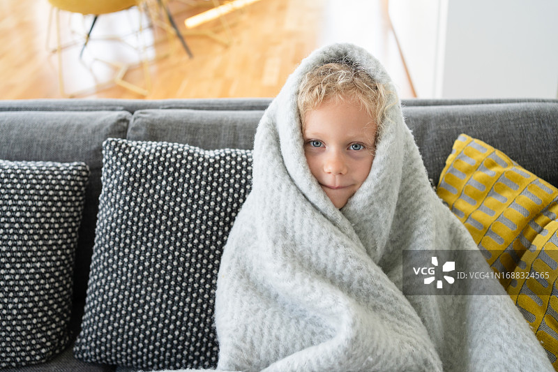 裹着毯子坐在客厅沙发上的悲伤女孩图片素材