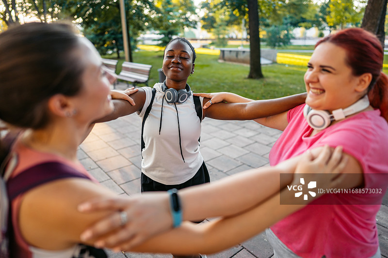 公园里锻炼后拥抱的三位年轻女性朋友图片素材