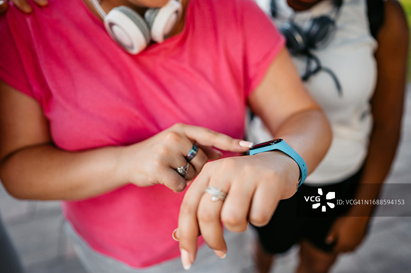 年轻女子在公园锻炼后查看智能手表上的健身数据图片素材