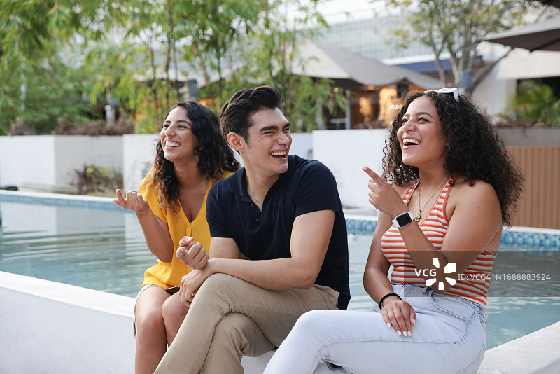 一小群年轻的拉丁裔人在购物区池塘边穿着休闲服装一起欢笑图片素材