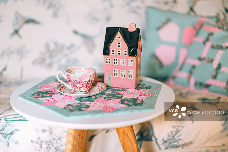 装饰着茶杯的粉色小屋小桌子。复古乡村风格浪漫舒适静物场景。早餐或放松时光。拼布装饰。斯堪的纳维亚风格图片素材