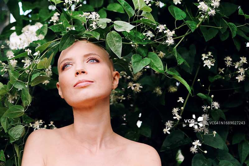 患有癌症或秃顶的年轻女孩肖像，特写鲜花，宛如女神。粉红十月图片素材