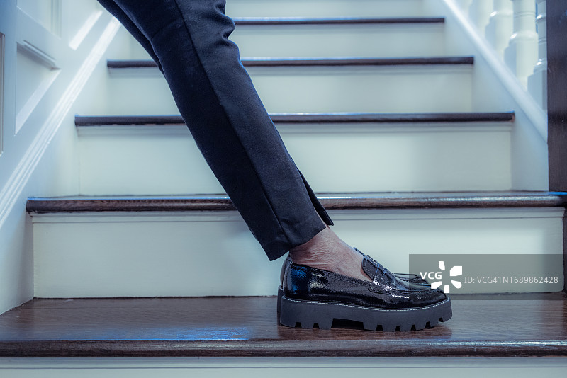 穿着黑裤和黑色乐福鞋站在楼梯上的黑人女性图片素材