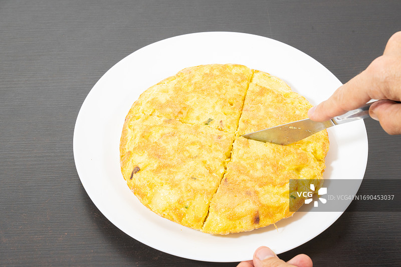 一个人将西班牙土豆饼切成块图片素材