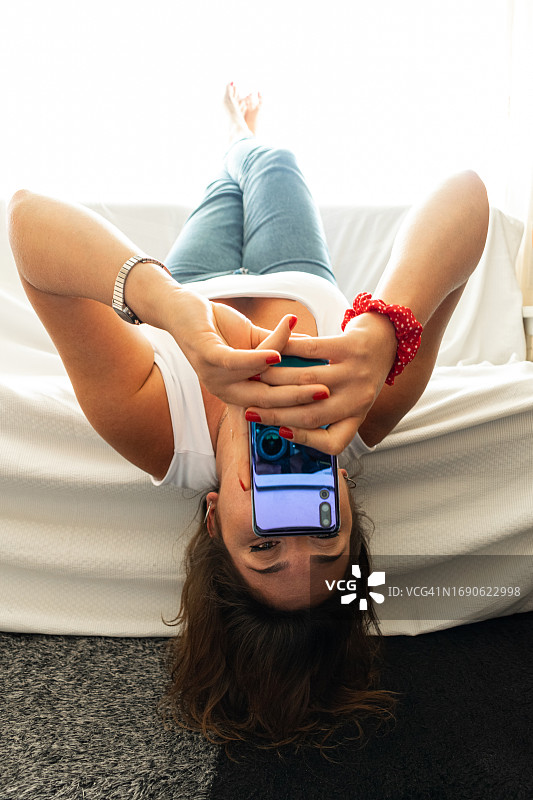 倒躺在沙发上玩手机的女人图片素材