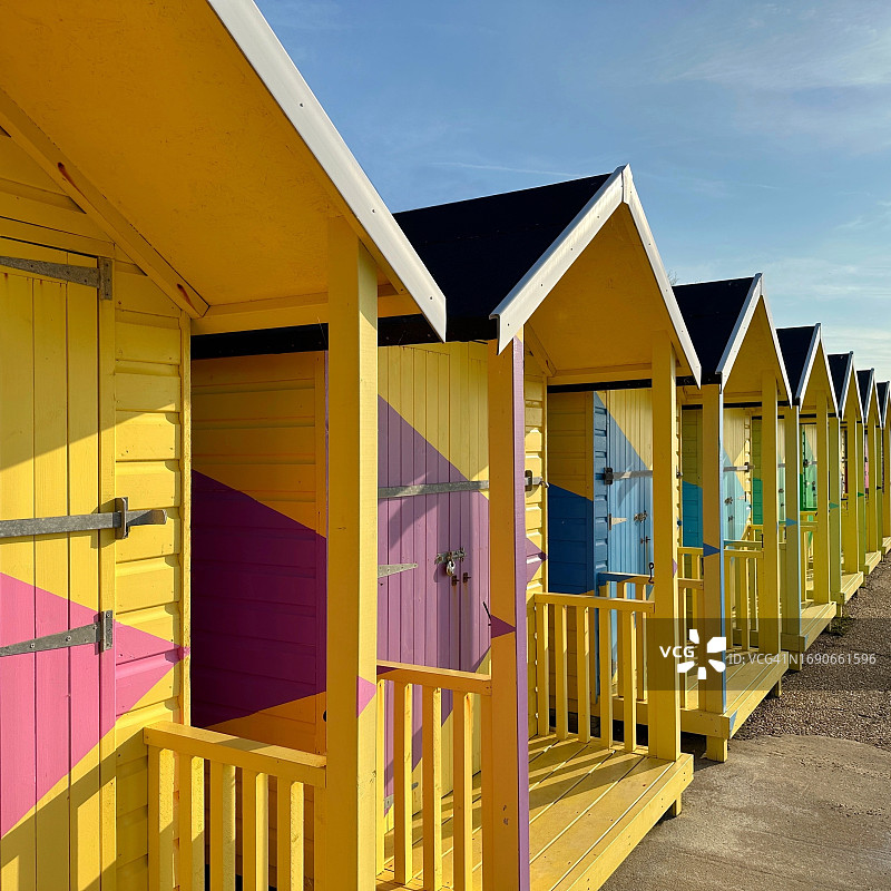 英国肯特郡福克斯通海滩上一排彩色木制海滩小屋图片素材