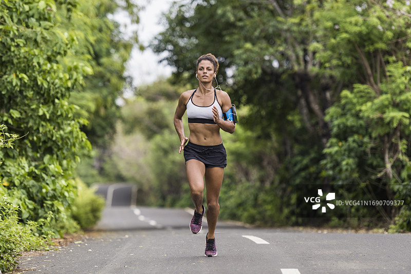 多种族女人在训练时沿着绿树成荫的乡村道路跑步图片素材