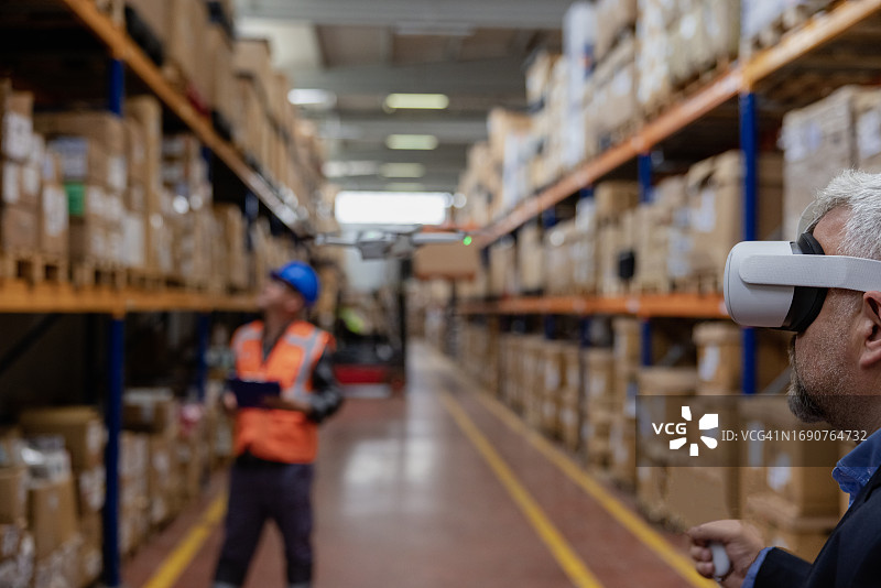 创新工业检测：商人利用VR头显和无人机进行仓库监控图片素材