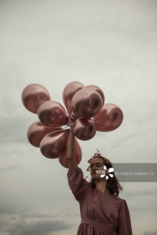拿着金属桃色气球的年轻女孩图片素材