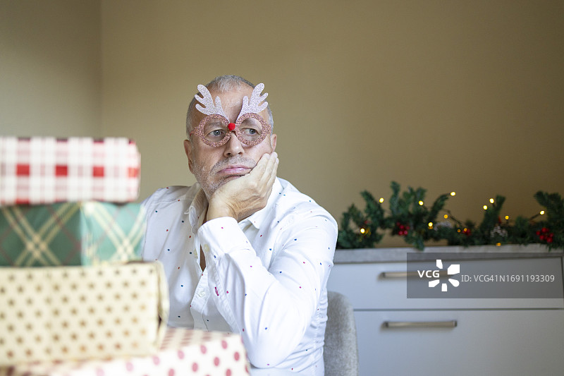 拿着圣诞礼物的悲伤的中年男人图片素材