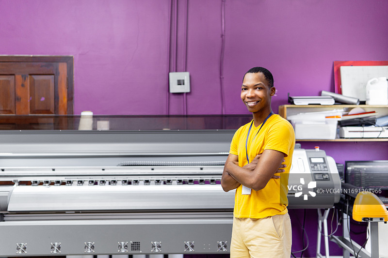 印刷店里一位笑容满面的男员工的肖像，看着镜头微笑。图片素材