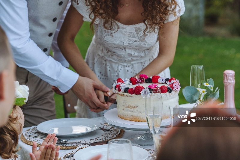 新娘和新郎握着刀切结婚蛋糕图片素材