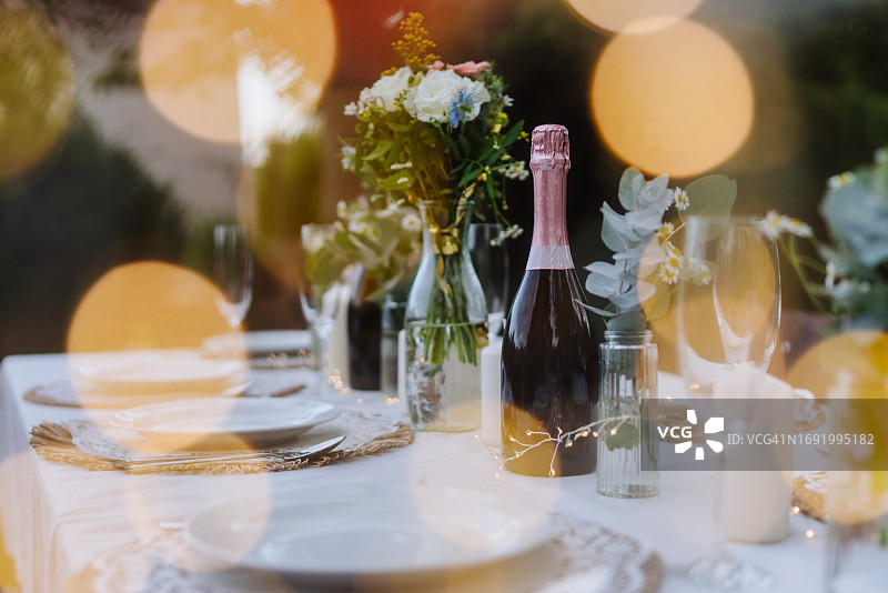 婚礼餐桌，香槟酒瓶、餐具和优雅婚礼装饰照片图片素材