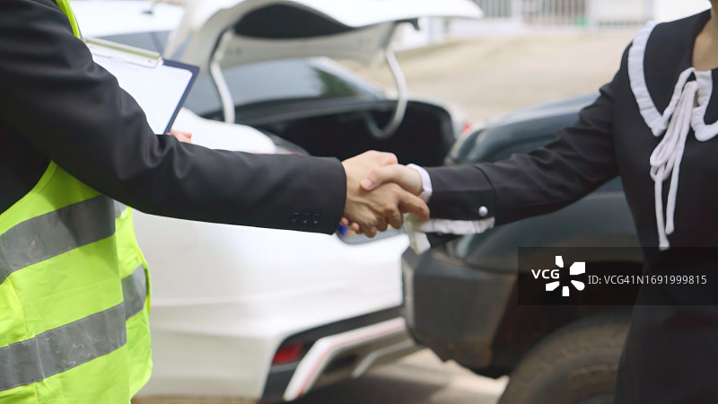 保险代理人与遇到汽车问题的妇女握手，理赔员评估汽车损坏图片素材