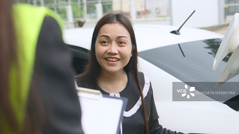 车祸后在路上与保险代理人交谈的亚洲女人图片素材