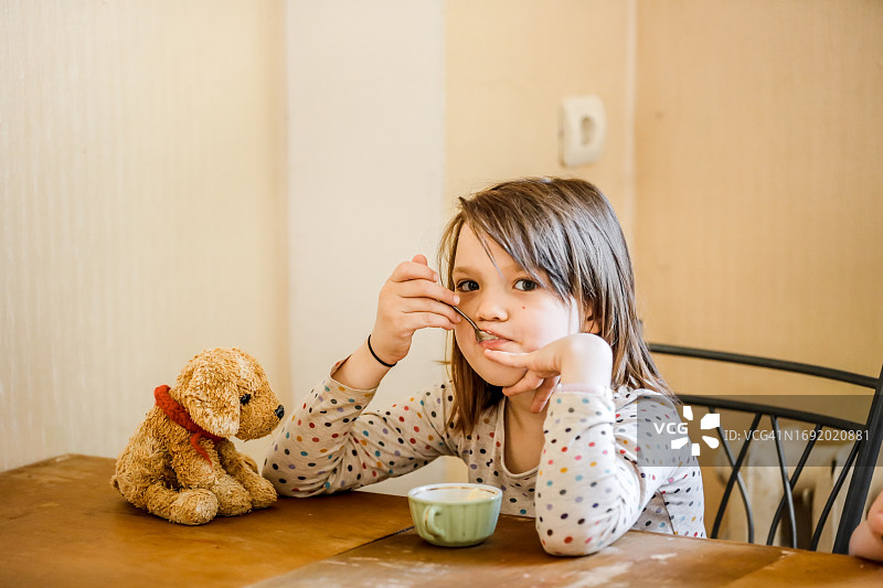 若有所思的年轻女孩和玩具狗坐在桌旁图片素材