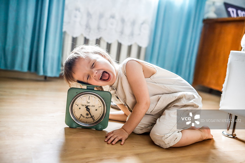 有趣的儿童将头放在老式厨房秤上，一张关于测定智力的搞笑照片图片素材