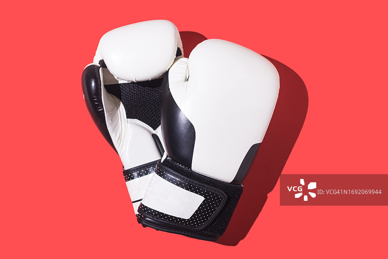 红色背景上的黑白拳击手套。拳击、运动、格斗、侵略、战斗、训练、努力、力量、可变性和体育精神的概念。图片素材