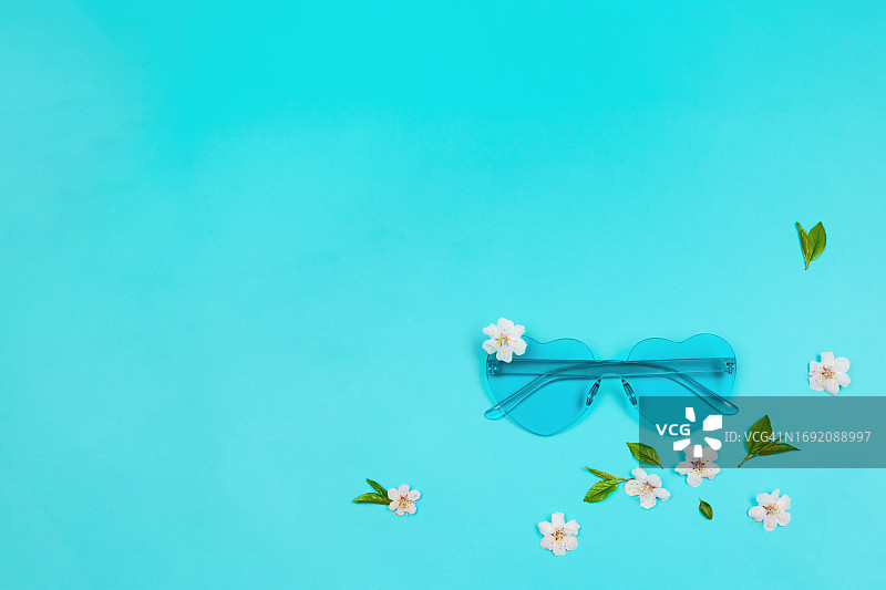 蓝色心形太阳镜与白色花朵的春季组合图片素材