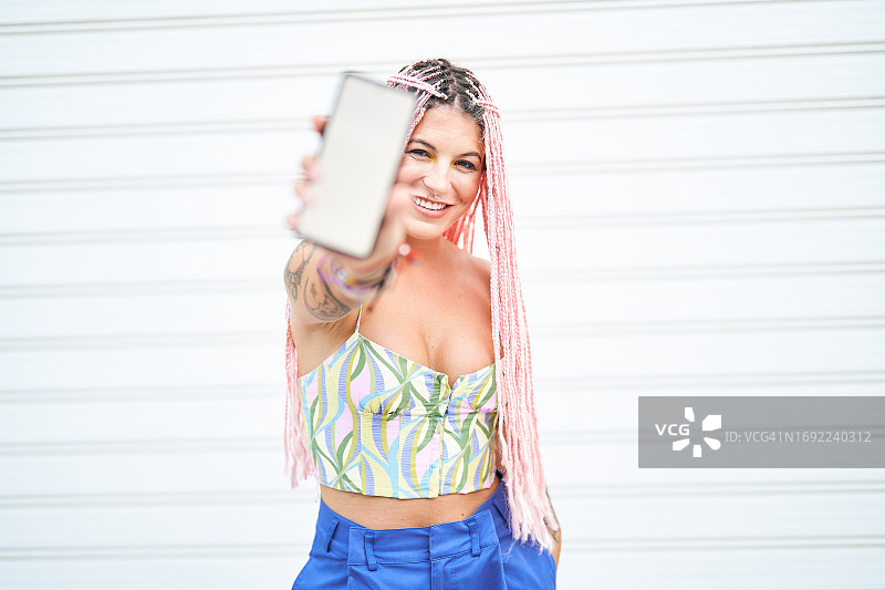 在白色背景上向镜头展示手机的漂亮女孩图片素材