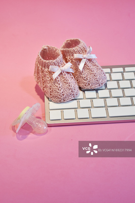 键盘上的粉色婴儿鞋，代表职场妈妈图片素材