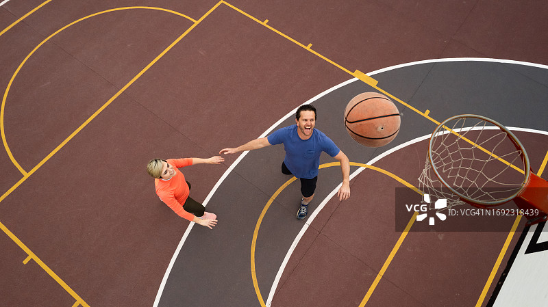 情侣在篮球场上休闲地打篮球（高角度拍摄）图片素材