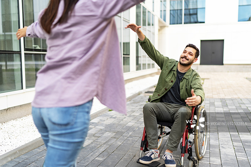 女人奔跑着拥抱坐在轮椅上的男人图片素材