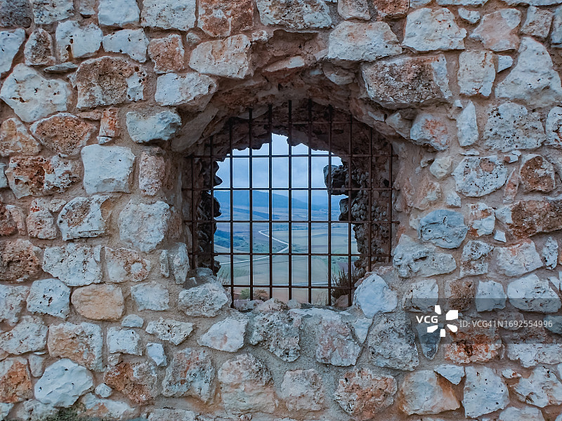 石墙上的带格栅的窗户，背景是西班牙瓜达拉哈拉省阿蒂恩萨的风景图片素材