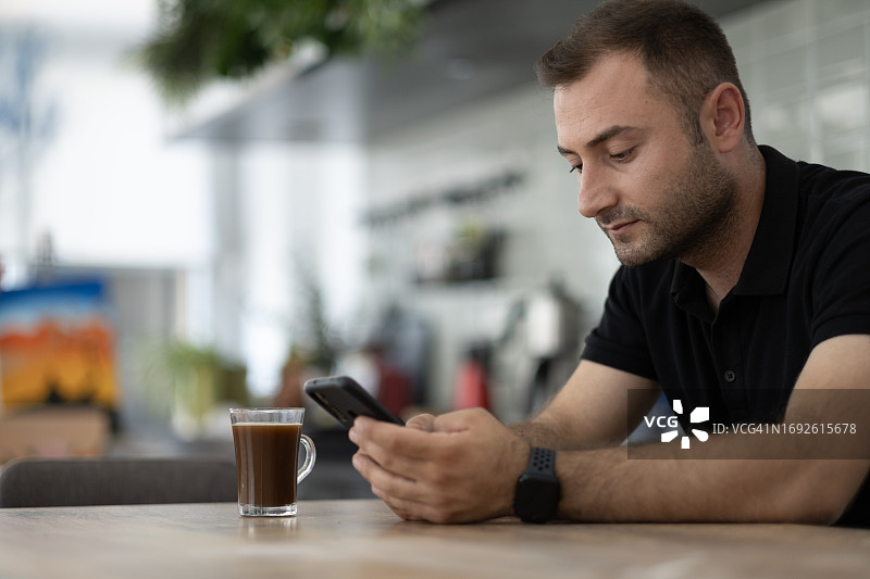 年轻男艺术家围着围裙在使用手机图片素材